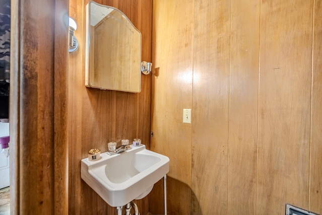 bathroom featuring wooden walls and sink