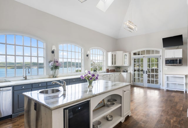 kitchen featuring a water view, an island with sink, wine cooler, and white cabinetry