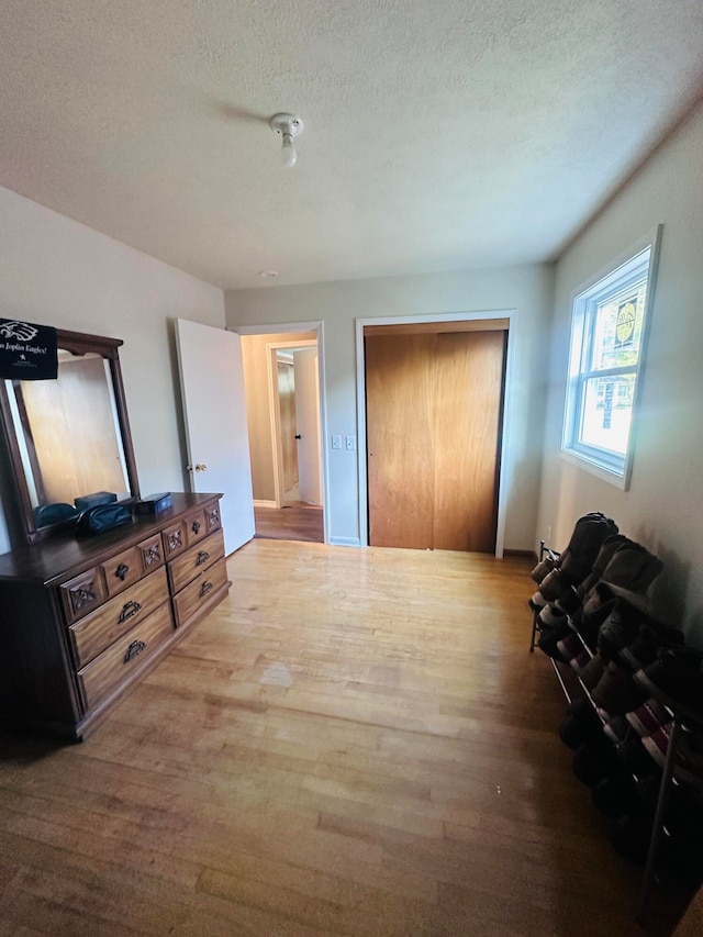 bedroom with a textured ceiling, a closet, and light hardwood / wood-style floors