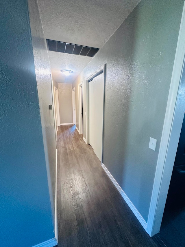 corridor with hardwood / wood-style floors and a textured ceiling