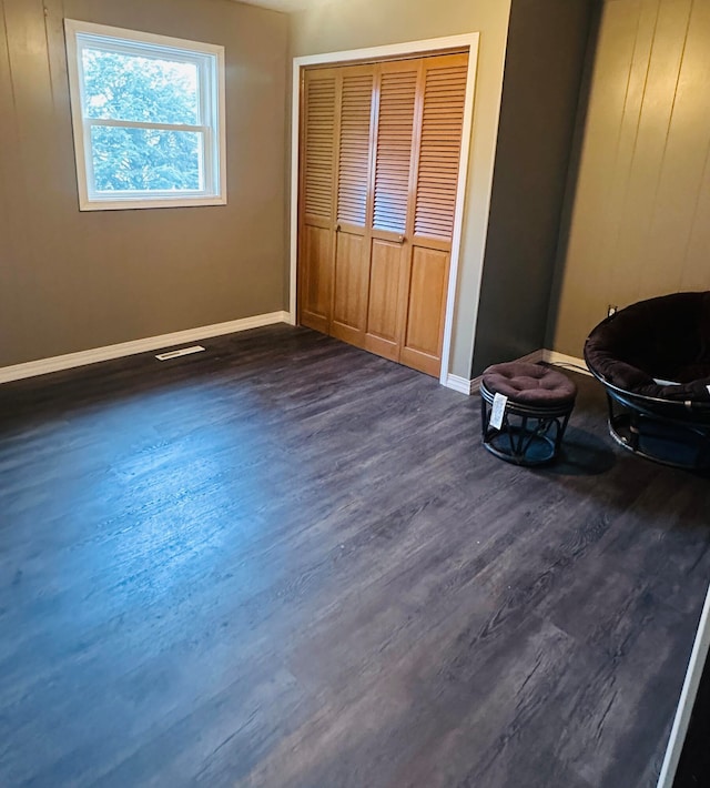 unfurnished bedroom with dark wood-type flooring and a closet