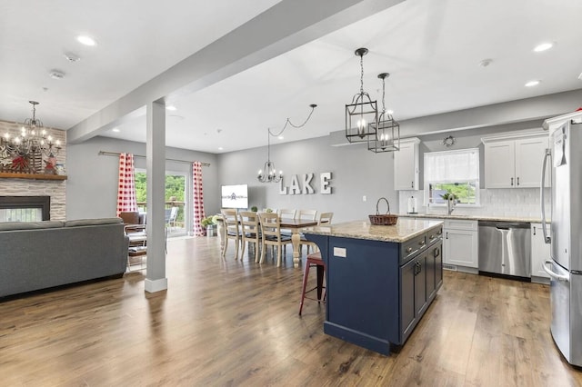 kitchen with a center island, white cabinets, pendant lighting, appliances with stainless steel finishes, and a healthy amount of sunlight