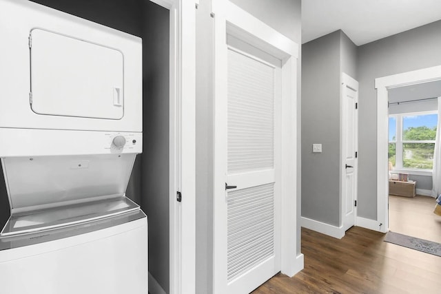 laundry area featuring stacked washer / dryer and dark wood-type flooring