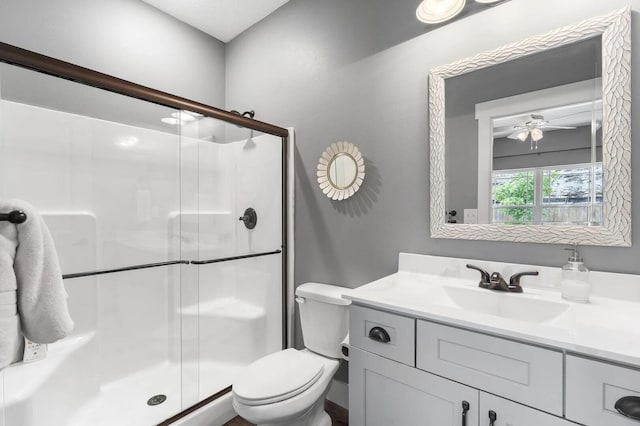 bathroom featuring ceiling fan, vanity, toilet, and a shower with door