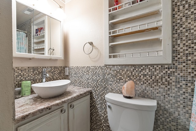 bathroom with toilet, tile walls, and vanity