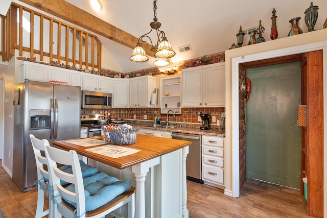 kitchen featuring white cabinets, hanging light fixtures, a kitchen island, appliances with stainless steel finishes, and light hardwood / wood-style floors