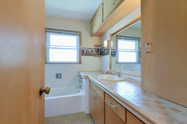 bathroom with a tub to relax in, vanity, a healthy amount of sunlight, and tile patterned flooring