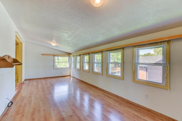 interior space with lofted ceiling, a textured ceiling, and light hardwood / wood-style floors