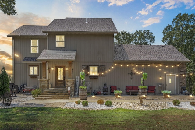 back house at dusk with a patio and a lawn