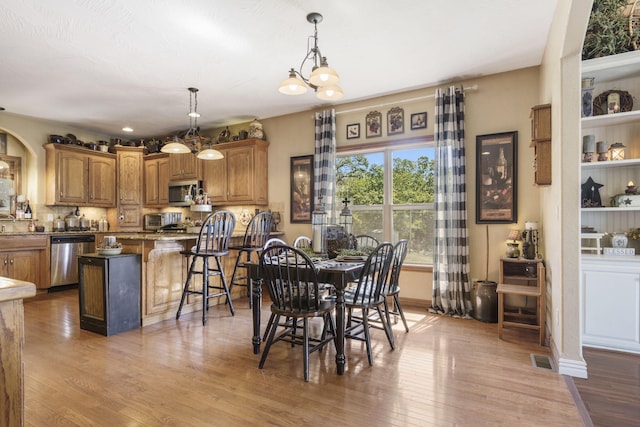 dining area with a notable chandelier and light hardwood / wood-style floors