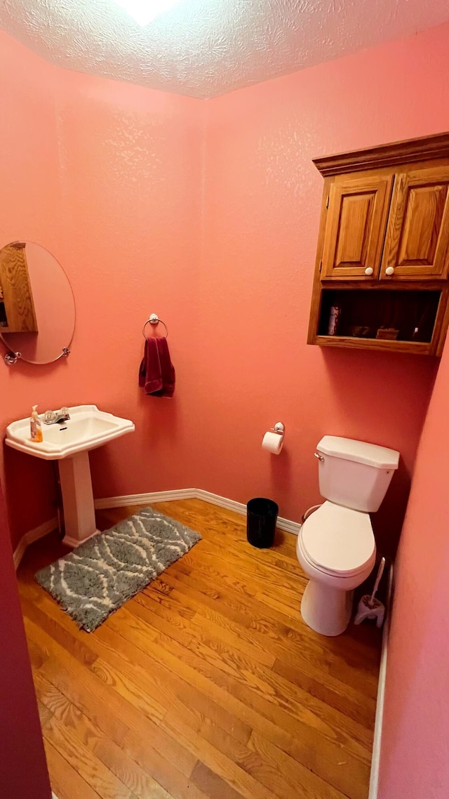 bathroom featuring hardwood / wood-style flooring, a textured ceiling, and toilet