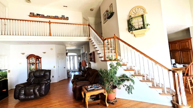 living room with wood-type flooring and a towering ceiling