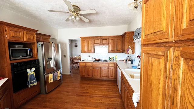 kitchen with a textured ceiling, sink, dark wood-type flooring, and black appliances