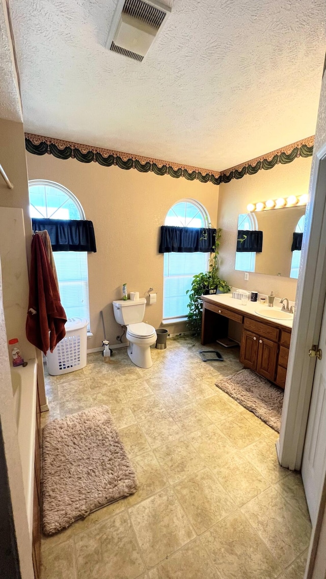 bathroom with vanity, toilet, and a textured ceiling