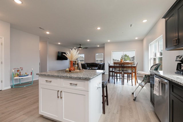 kitchen featuring light hardwood / wood-style floors, light stone counters, stainless steel dishwasher, and white cabinetry