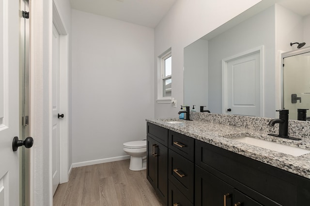 bathroom featuring hardwood / wood-style flooring, toilet, walk in shower, and vanity