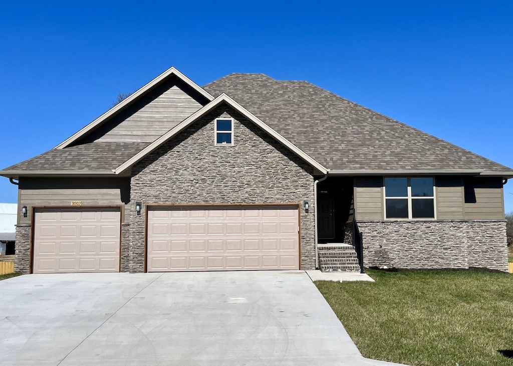 craftsman inspired home featuring concrete driveway, stone siding, roof with shingles, a front yard, and a garage