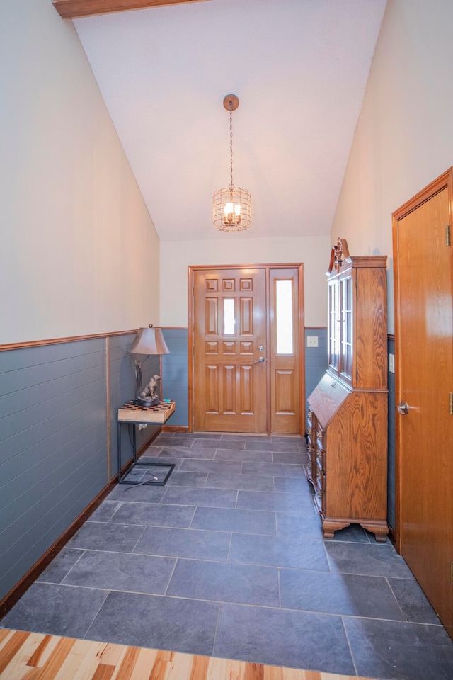 foyer entrance featuring dark wood-type flooring, a notable chandelier, and lofted ceiling with beams