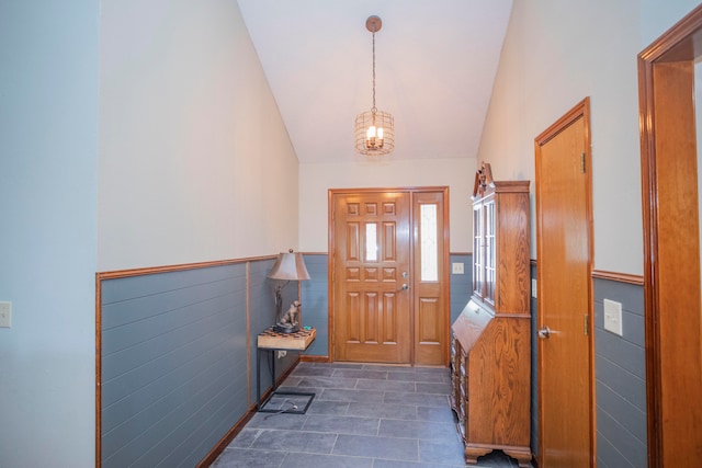 entrance foyer featuring a notable chandelier, tile walls, and vaulted ceiling