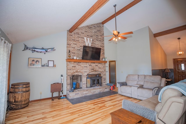 living room with a brick fireplace, beamed ceiling, ceiling fan, and light hardwood / wood-style flooring