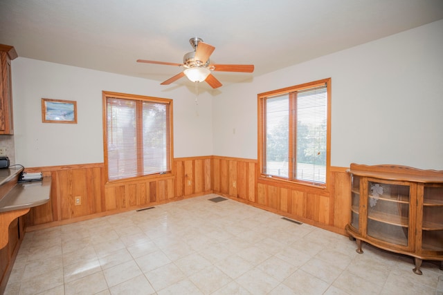 home office featuring wood walls and ceiling fan