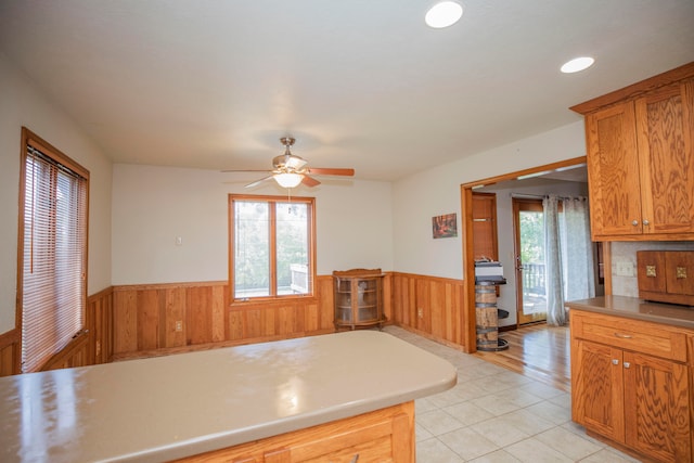 kitchen with ceiling fan, wood walls, and light tile patterned floors