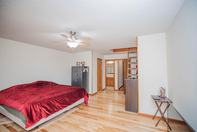 bedroom featuring a textured ceiling, connected bathroom, light wood-type flooring, and ceiling fan