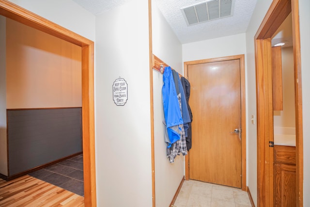 hallway featuring a textured ceiling and light hardwood / wood-style floors