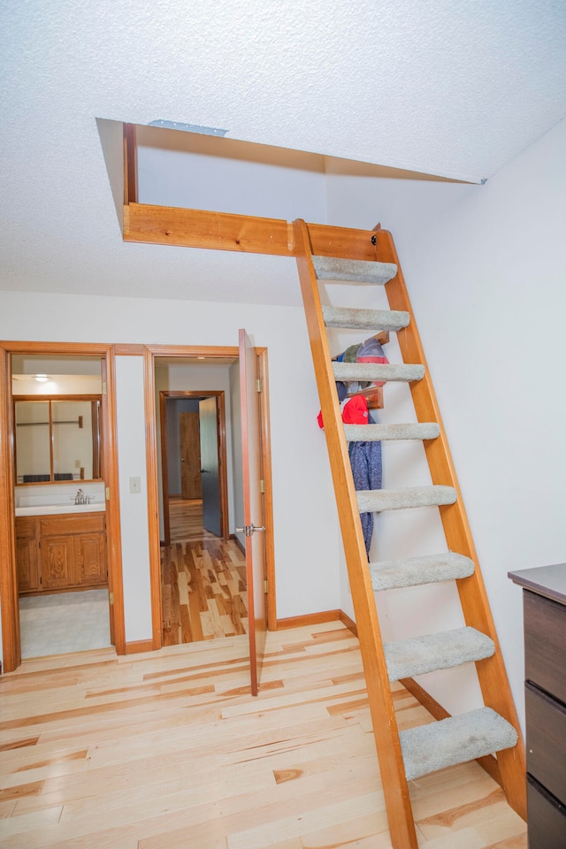 stairway with hardwood / wood-style flooring, a textured ceiling, and sink