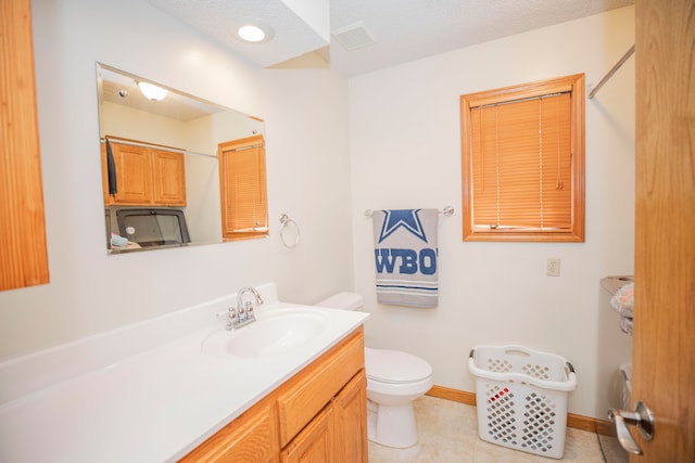 bathroom with tile patterned flooring, a textured ceiling, vanity, and toilet