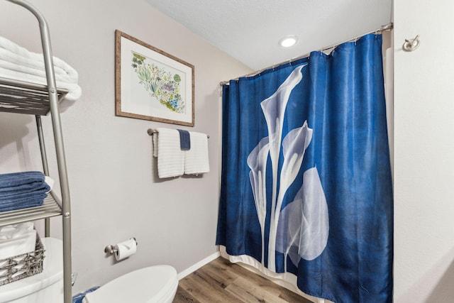 bathroom with toilet, wood-type flooring, and a textured ceiling