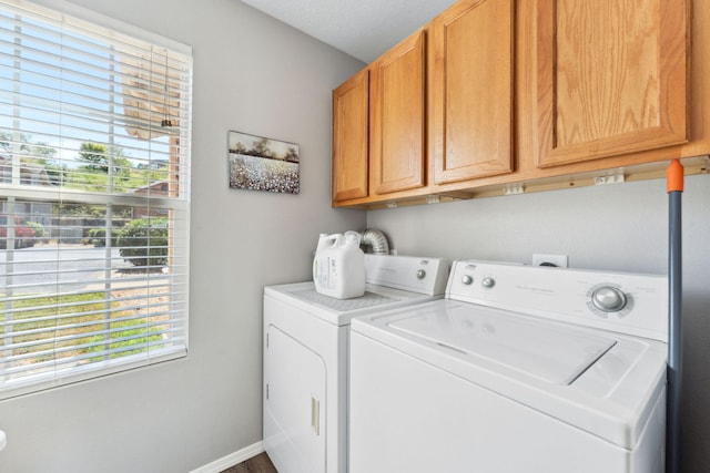 clothes washing area with a textured ceiling, a wealth of natural light, washing machine and clothes dryer, and cabinets