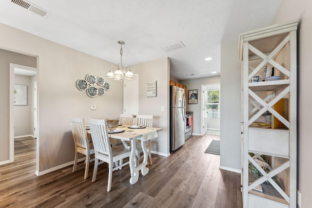 dining room with dark wood-type flooring, an inviting chandelier, and a textured ceiling