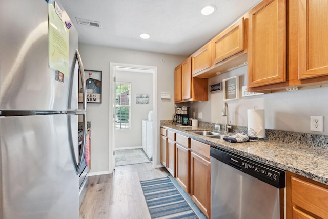 kitchen with light hardwood / wood-style flooring, appliances with stainless steel finishes, sink, and light stone counters