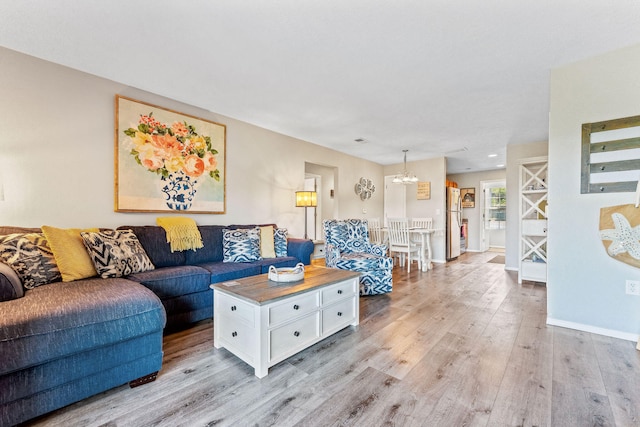 living room with light wood-type flooring and an inviting chandelier