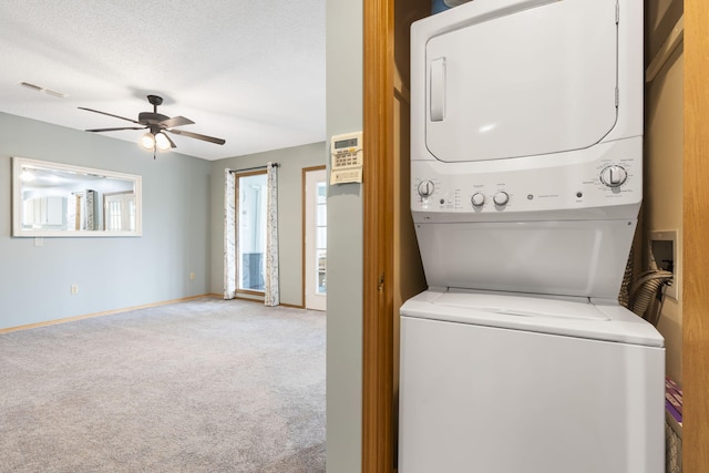 laundry area with ceiling fan, stacked washer and clothes dryer, carpet floors, and a textured ceiling