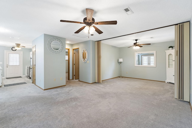 unfurnished living room with a textured ceiling, ceiling fan, and light colored carpet