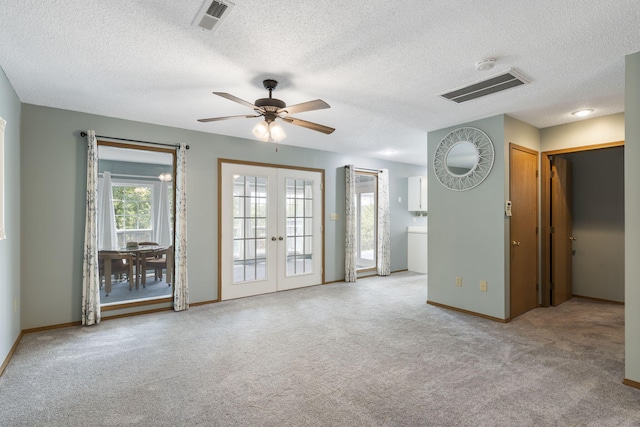 carpeted spare room with ceiling fan, french doors, and a textured ceiling