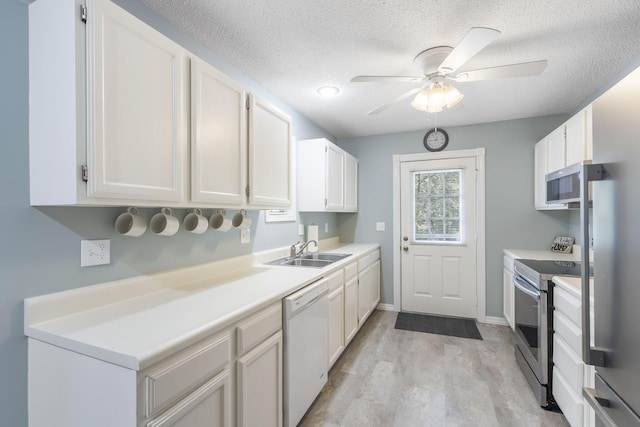 kitchen with appliances with stainless steel finishes, white cabinetry, sink, and light hardwood / wood-style floors