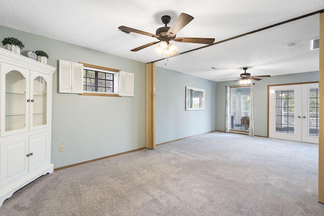 carpeted empty room featuring ceiling fan, french doors, and a textured ceiling