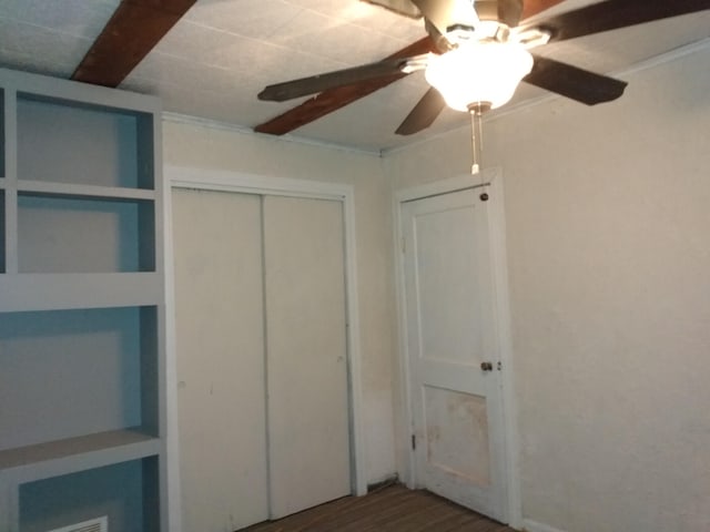 unfurnished bedroom with ceiling fan, dark wood-type flooring, and a closet