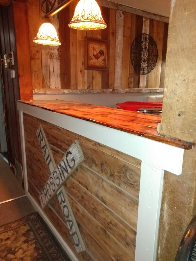 bar featuring wood walls and hanging light fixtures