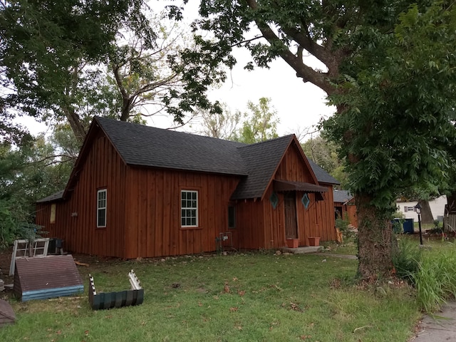 exterior space with a lawn, roof with shingles, and board and batten siding