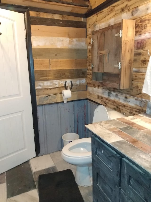 bathroom with wooden walls, vanity, and toilet