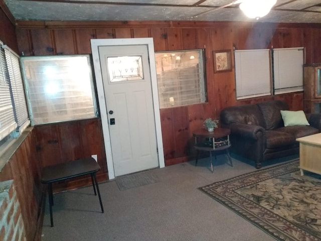 carpeted foyer entrance with wood walls