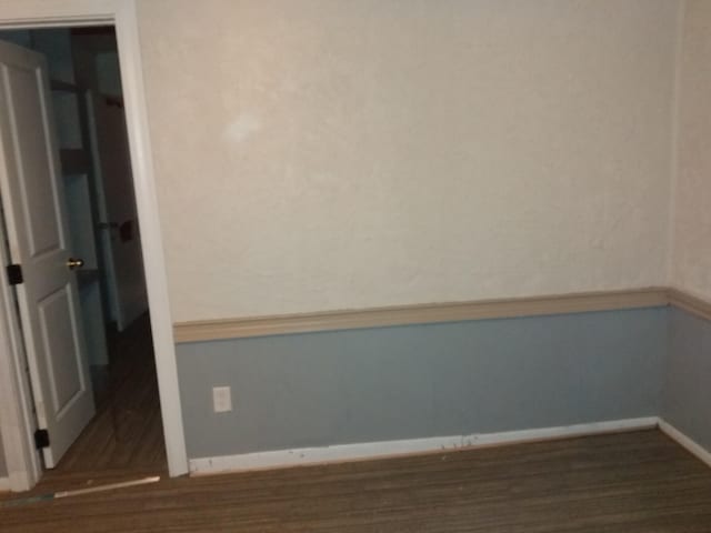spare room featuring baseboards and wood finished floors