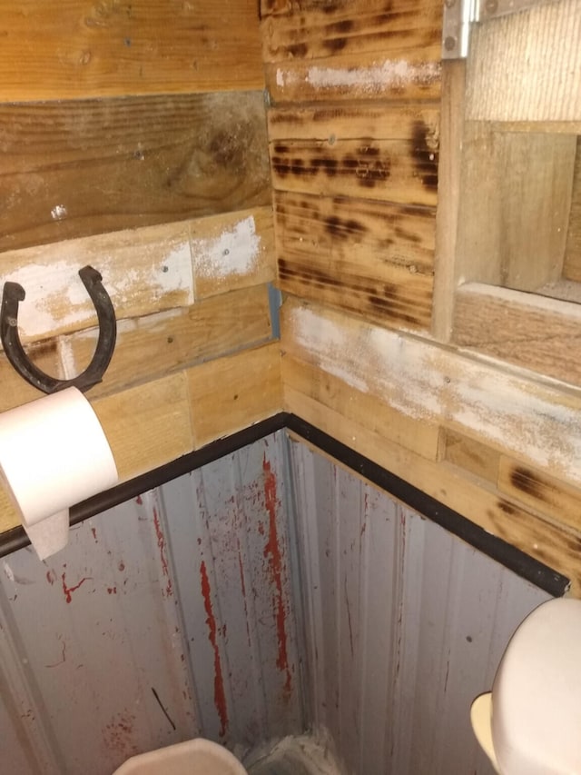 bathroom featuring wooden walls and toilet