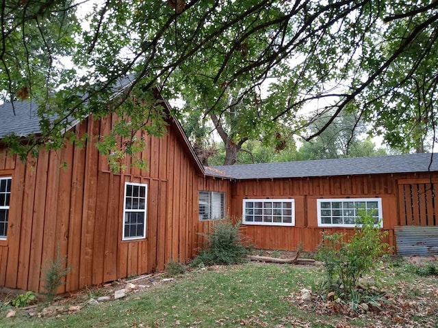 view of side of home featuring board and batten siding and roof with shingles