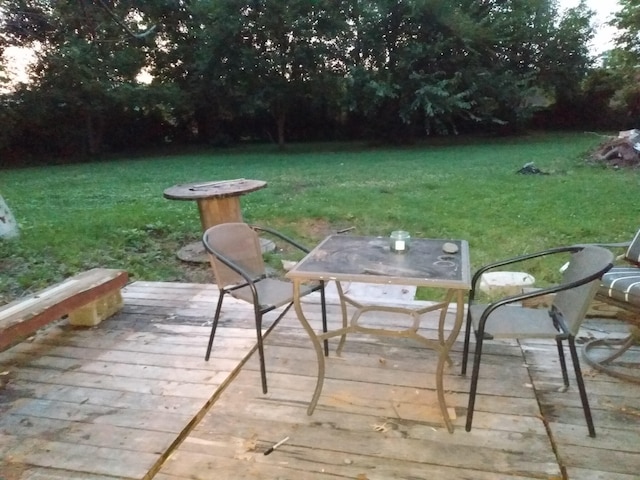 wooden terrace featuring outdoor dining area and a yard