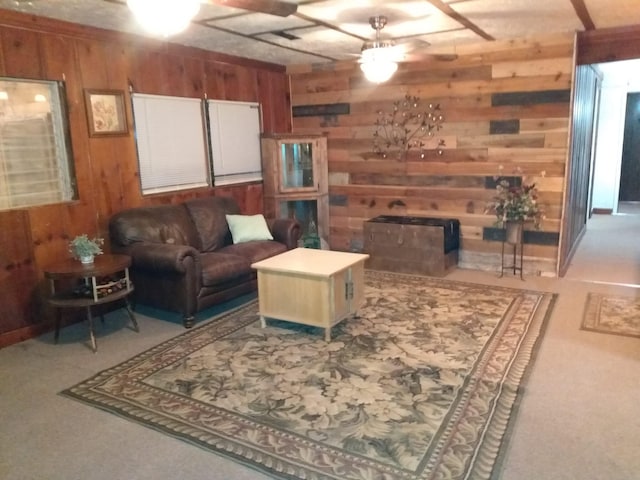 carpeted living room with a fireplace, wooden walls, and a ceiling fan